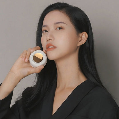 Woman holding a mini clip fan on a plain background