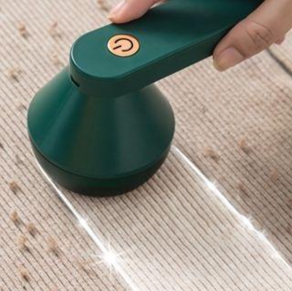 A green handheld lint remover cleaner being used on a carpet
