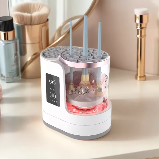 A white and gray electronic makeup brush cleaner on a vanity table with cosmetic items in the background