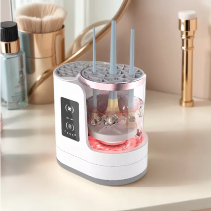 A white and gray electronic makeup brush cleaner on a vanity table with cosmetic items in the background